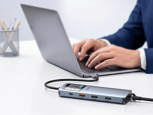 Person using a laptop connected to a multi-port USB-C docking station on a clean office desk